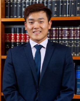 Lawyer smiling in office with legal books in background.