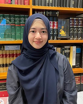 Team member in professional attire wearing a hijab in a law library.